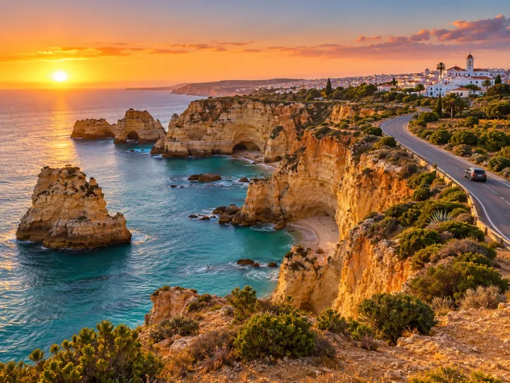 Travel inspiration: a coastal road above golden cliffs and turquoise water.