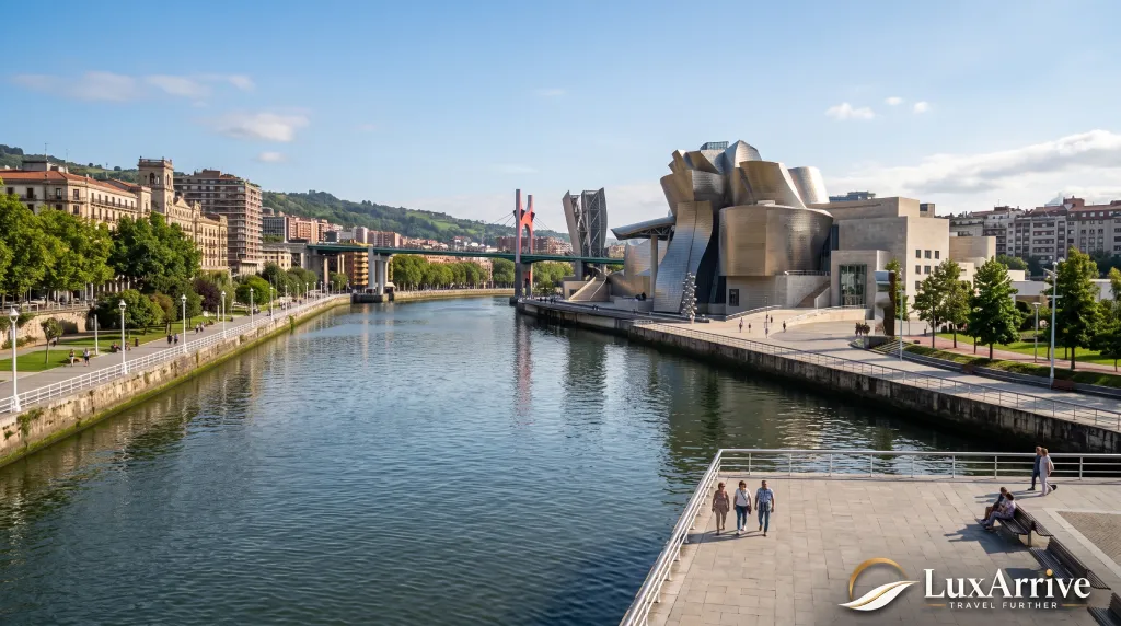 A paved waterfront walkway along the river in Bilbao with the Guggenheim Museum in the distance.