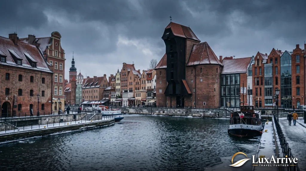 The Gdansk waterfront and medieval crane along the Motława River under a dark winter sky.